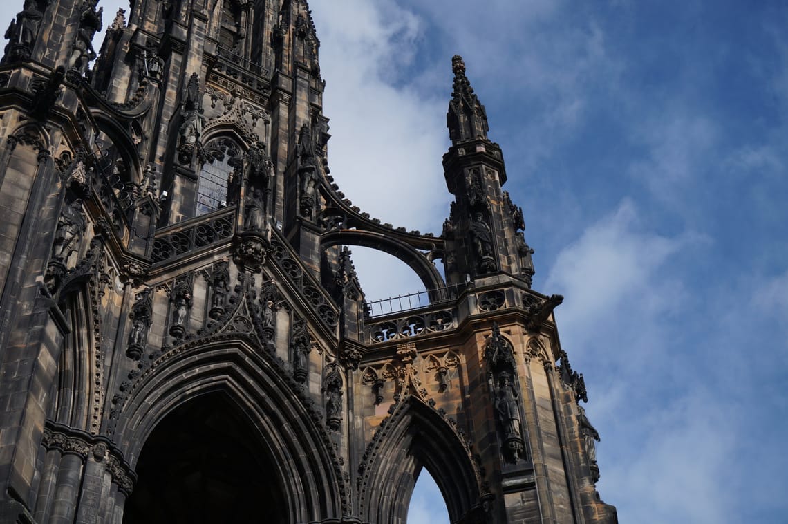A picture of part of the Scott Monutment in Edinburgh against a blue, lightly cloudy sky